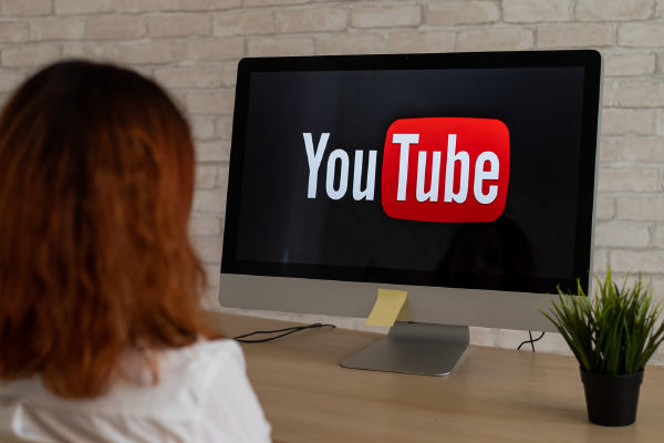 Woman sitting at a computer with a Youtube logo on the screen