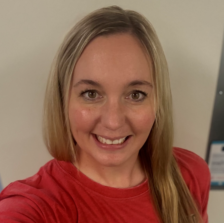 Faith_Anderson_cropped Image of women with long blond hair, brown eyes, smiling with red t-shirt on with tan background.