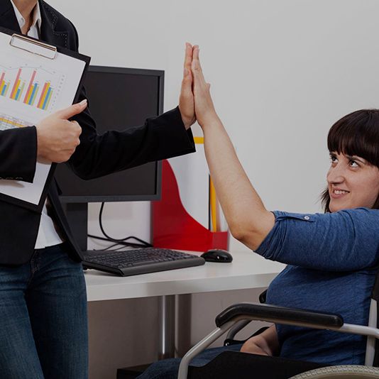 Women in wheelchair high fiving another person Women in wheelchair high fiving another person